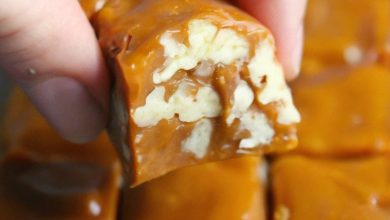 piece of caramel fudge with visible nuts embedded within. The fudge is a rich, golden-brown color