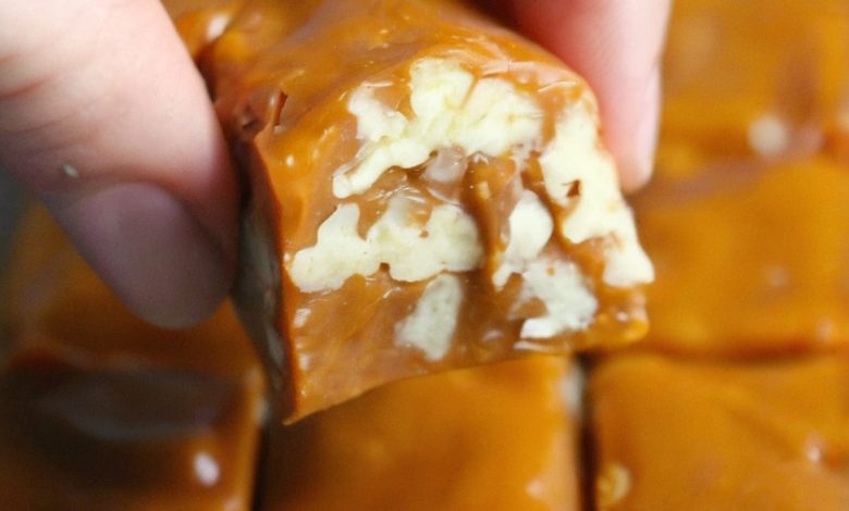 piece of caramel fudge with visible nuts embedded within. The fudge is a rich, golden-brown color