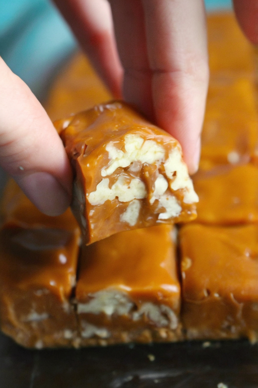 piece of caramel fudge with visible nuts embedded within. The fudge is a rich, golden-brown color